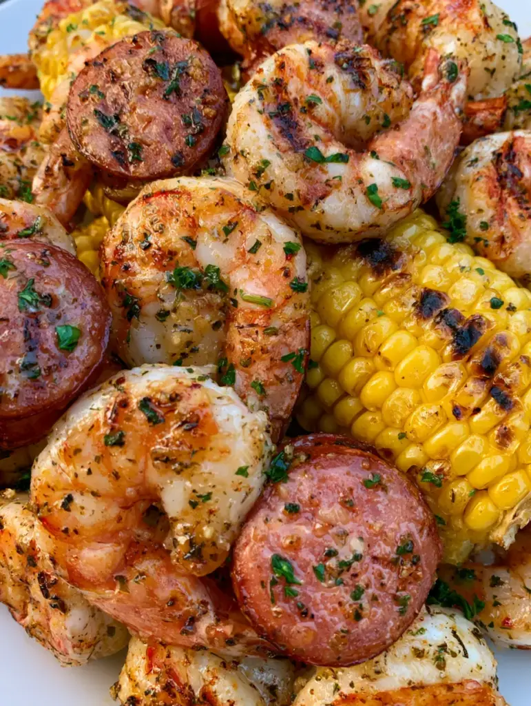 Rondelles de maïs jaune vif et saucisses fumées avec grains caramélisés et persil frais. (brochettes crevettes et saucisses)